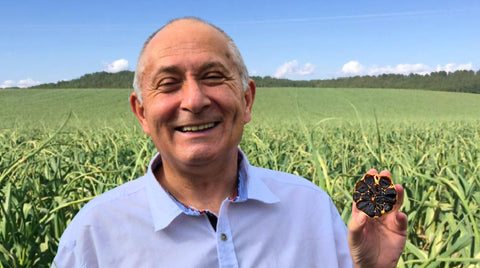 Daniel Gonzalez, Inhaber von Black Gonzalez, hält lächelnd eine aufgeschnittene Knolle schwarzen Knoblauchs in der Hand