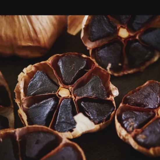 Nahaufnahme von schwarzen Knoblauch Knollen, die aufgeschnitten wurden, zeigt die dunkle, klebrige Innenseite und die weiche Textur.