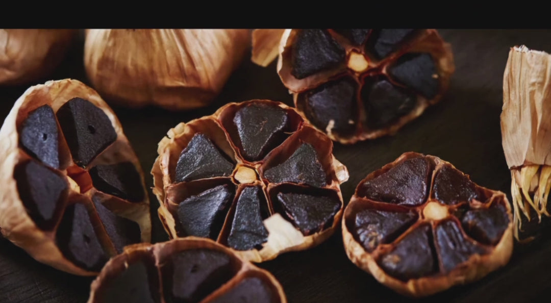 Nahaufnahme von schwarzen Knoblauch Knollen, die aufgeschnitten wurden, zeigt die dunkle, klebrige Innenseite und die weiche Textur.