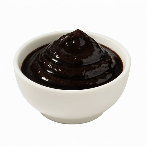 Schwarzer Knoblauch Honig in weißer Schüssel auf weißem Hintergrund – fermentierter Knoblauch in Honig als Feinkostprodukt